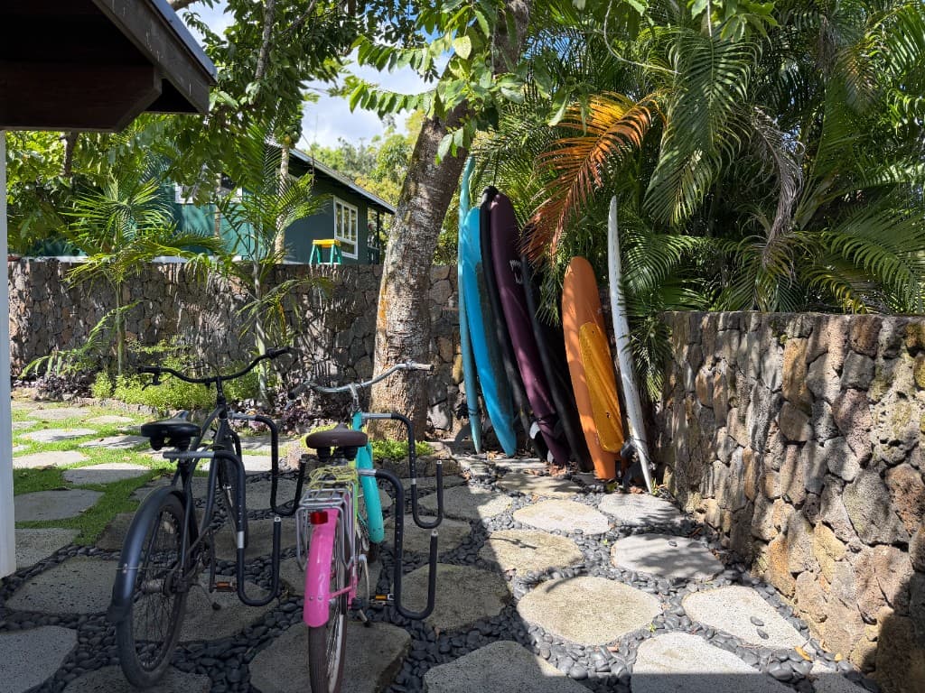 Beach cruisers with surf racks beside boards and tropical landscaping